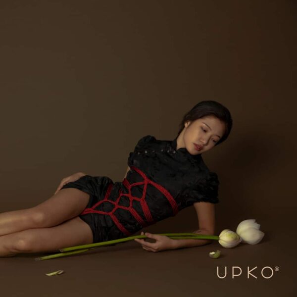 Rotes Shibari-Seil der Marke UPKO. Das Model trägt ein Seilgeflecht mit einer Länge von 10 m und einem Seildurchmesser von 6 mm.