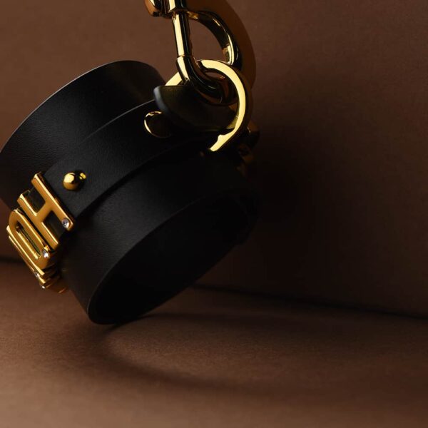 Close-up of a black Italian leather handcuff with 24-carat gold-plated and engraved hooks by UPKO for the limited edition UPKO X Brigade Mondaine at Brigade Mondaine