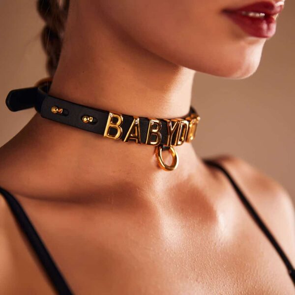 Choker aus der Zusammenarbeit von Brigade Mondaine und Upko. Die Basis des Chokers ist aus italienischem Leder gefertigt und jeder Buchstabe ist mit 24 Karat vergoldet und mit je einem Kristall besetzt.