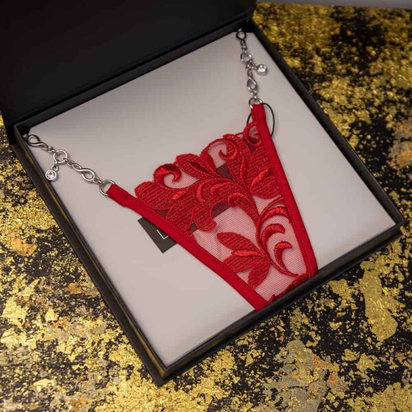 Lucky Cheeks String aus der Love Story-Kollektion. Der String ist rot und besteht aus Blumenstickereien sowie Mesh. Außerdem verfügt er über einen Verschluss aus einer versilberten Zamak-Schmuckkette.