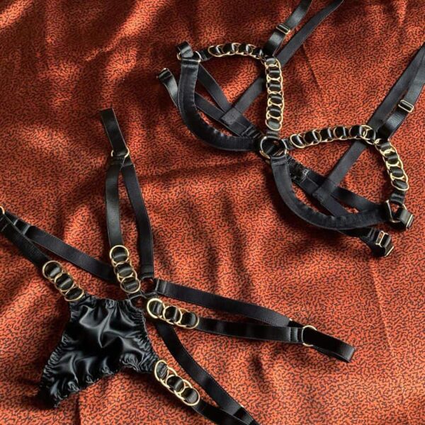 Sehr sexy schwarzes BH- und String-Set, das im Brustbereich und an den Hüften offen ist. Das Set ist mit goldenen Kreisen verziert.