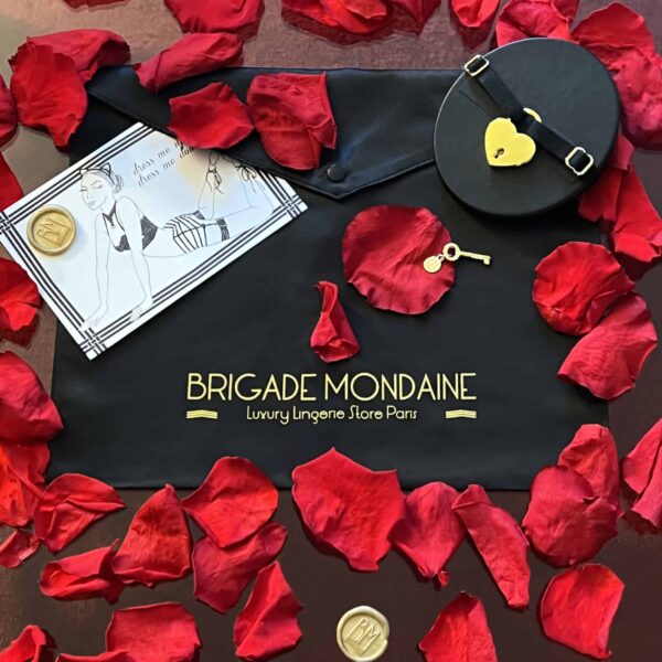 Упаковка черного цвета с символикой «Brigade Mondaine». На ткани золотистыми буквами нанесена надпись «Brigade Mondaine». В комплект входят открытка, черный чокер и лепестки роз. .