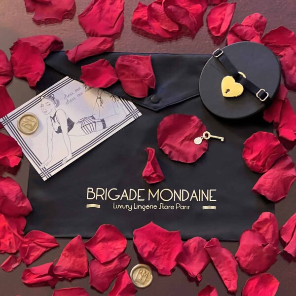 Упаковка черного цвета с символикой «Brigade Mondaine». На ткани золотистыми буквами нанесена надпись «Brigade Mondaine». В комплект входят открытка, черный чокер и лепестки роз. .