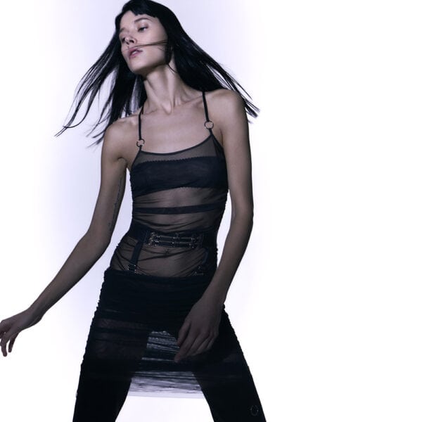 Top and skirt set Les Indolentes Collection Caravasar from the brand Gonzales Affaires. This skirt stops below the knees. The product is made from a part of gray transparent tulle from the knees to the navel. A seam is located on the side of the dress in order to obtain or not a pleated rendering of the skirt by grabbing the ring at the end of the skirt. Then a belt is placed at the level of the hips with three thin elastics decorated with silver rings in the center of the belt. The two parts are connected by two elastic bands that are removable through two hooks. This top is made of gray transparent tulle. A struck effect is present at the level of the belly. A seam on the right side of the top allows to obtain this effect even more pronounced when you pull the ring at the end of this seam. The straps are both joined on the shoulder and thus give an asymmetrical aspect. Two silver rings embellish these straps. At the back, the top of the back is bare and the two straps meet in one through a ring and an adjustable elastic band that is sewn on the top. The top and skirt are perfectly juxtaposed and form a tulle dress of great elegance.
