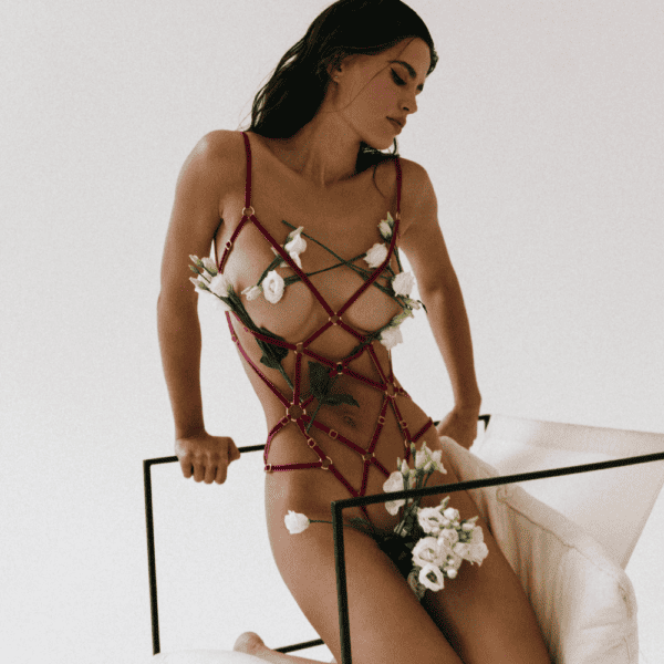 COUTURE DE NUIT - Stella Playsuit Fuchsia Photographie d'un corps de femme portant un playsuit fuchsia avec des fleurs blanches dispersées sur son corps avec le harnais.