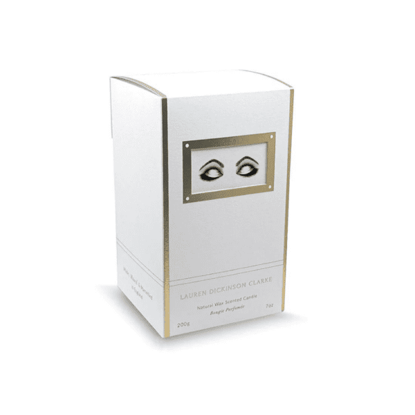 LDC - Ponderer Bougie Parfumée Le packaging de la bougie arbore une couleur blanche avec des touches dorées, et il est agrémenté d'un dessin représentant des yeux exprimant de la détente.