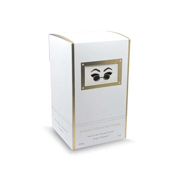 LDC - Vela perfumada Peacemaker Envase de vela en color blanco con detalles dorados, decorado con un motivo de ojos detrás de unas gafas.