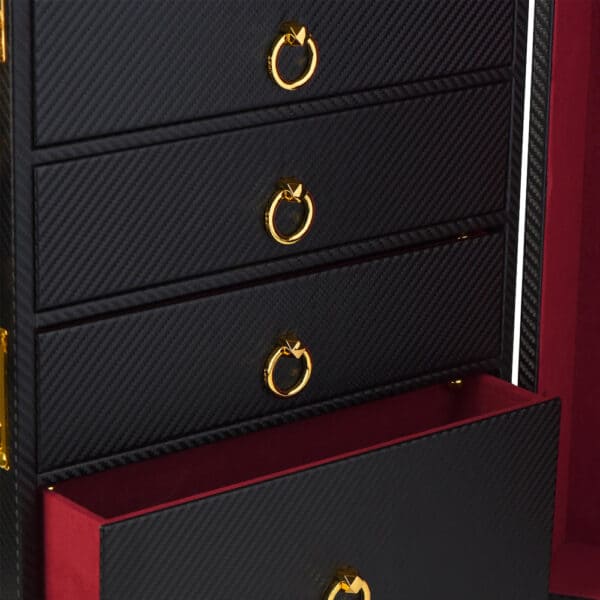 Photograph of the interior of a trunk showing black leather drawers with a red velvet bottom. The handles are in the form of gilded circles. .