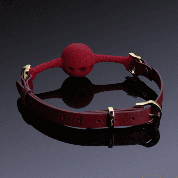 Image of red heart mouth gag on black background.