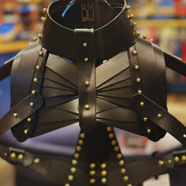 UNA BURKE - Schulterholster Leder Schwarzes Schulterholster aus Leder von Úna Burke, inspiriert von Waffenholstern, mit goldbeschichteten massiven Messingbeschlägen und Messingschrauben, die ein schickes, strukturiertes Rockstück schaffen, das von Ikonen wie Janet Jackson und Rihanna getragen wurde.