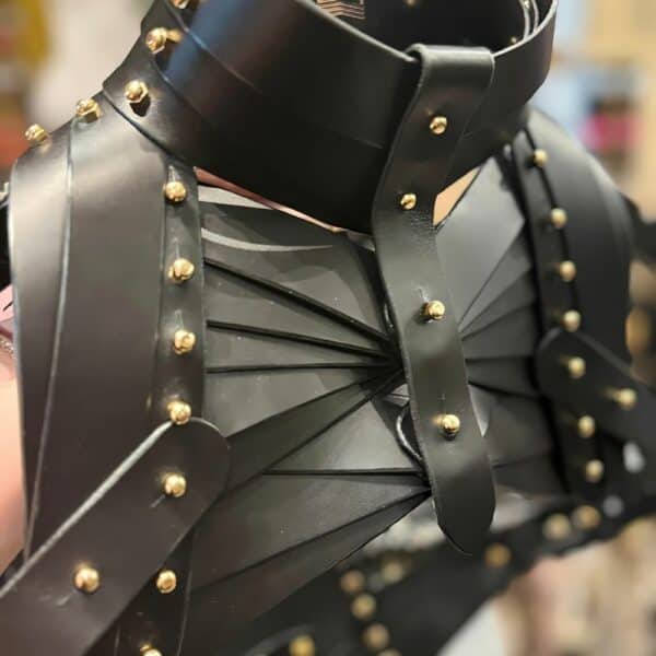 UNA BURKE - Schulterholster Leder Schwarzes Schulterholster aus Leder von Úna Burke, inspiriert von Waffenholstern, mit goldbeschichteten massiven Messingbeschlägen und Messingschrauben, die ein schickes, strukturiertes Rockstück schaffen, das von Ikonen wie Janet Jackson und Rihanna getragen wurde.
