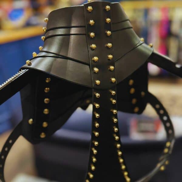 UNA BURKE - Schulterholster Leder Schwarzes Schulterholster aus Leder von Úna Burke, inspiriert von Waffenholstern, mit goldbeschichteten massiven Messingbeschlägen und Messingschrauben, die ein schickes, strukturiertes Rockstück schaffen, das von Ikonen wie Janet Jackson und Rihanna getragen wurde.