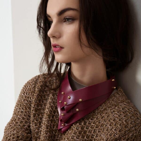 UNA BURKE LEATHER (10) Photographie du collier Turned de Una Burke en cuir bordeaux porté par une femme par dessus un pull.