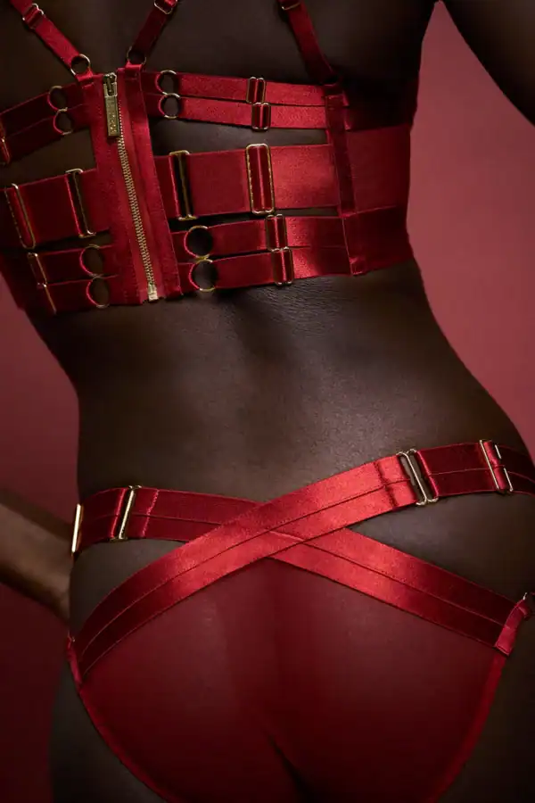 BORDELLE SIGNATURE BURNT RED Detailansicht des Fotos einer Frau von hinten, die einen trägerlosen BH und ein Strapshöschen in Rot trägt.