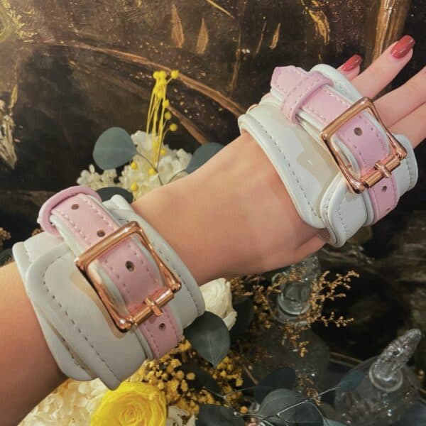 Esposas FAIRY bondage de cuero blanco y rosa con detalles en oro rosa. Ajustable con hebillas de metal y clips de liberación rápida para un ajuste seguro y cómodo. Perfectas para juegos BDSM.