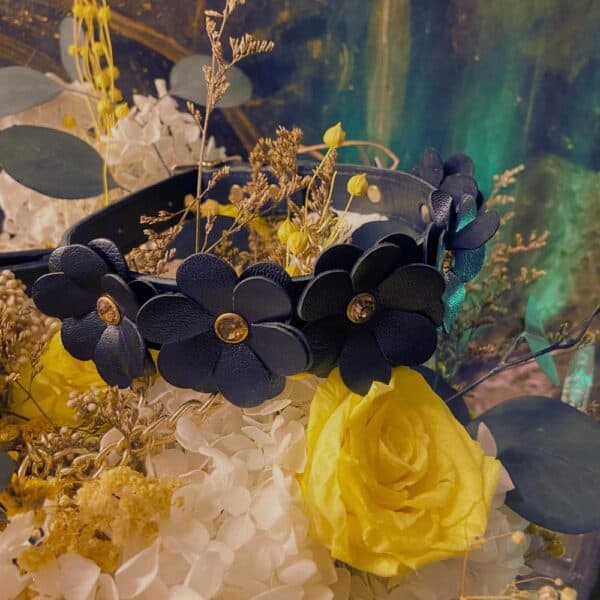 Leather necklace with flower design set on flowers.
