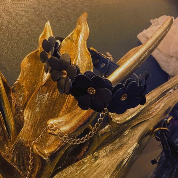 Black leather collar and lead with flower design and gold chain, set on a gold decoration