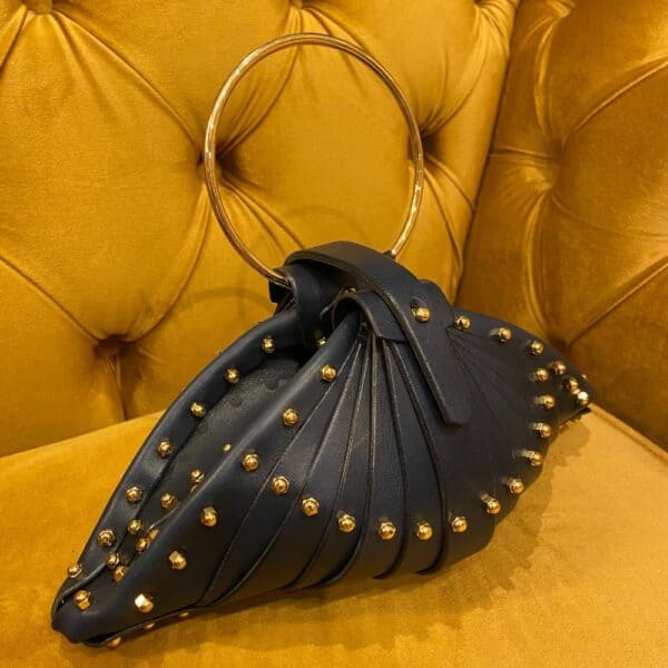 UNA BURKE - Sac Shell Blueberry Sac Blueberry Shell Bag de Úna Burke en cuir sculptural, raccords dorés, intérieur en cuir d'agneau, sangle en laiton poli, fabriqué à la main en Irlande. Confectionné avec cuir de vachette tanné végétal.