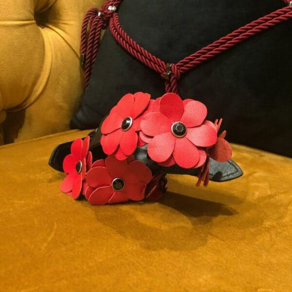 Bild mit Packshot von schwarzen Lederhandschellen mit roten Lederblumen und schwarzer Kette