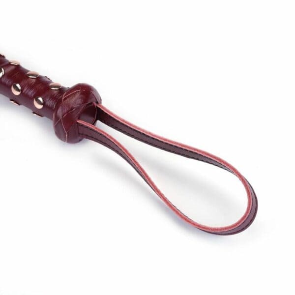 Détail du Packshot d'un Martinet avec un Manche en Cuir Rouge et Lanières en Cuir Noir
