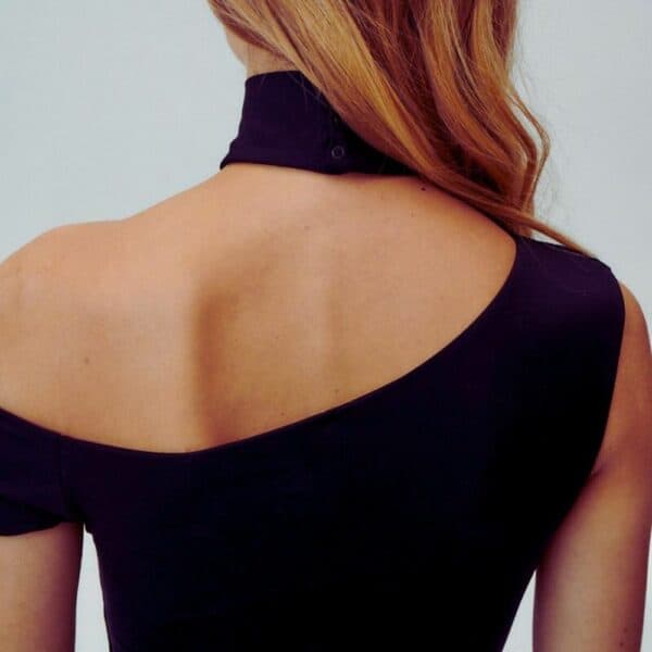 UNDRESS CODE - Body String VIRGO Détail sur la Coupe d'une Photo d'une Femme de Dos portant un Body Opaque Asymétrique et une Jupe Longue couleur Noir