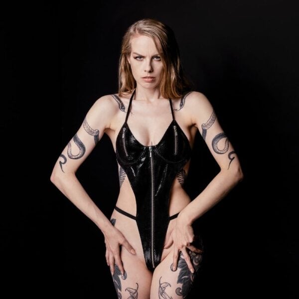 Foto einer Frau, die einen Body aus schwarzem, glänzendem Schafsleder mit Schlangenleder und silbernem Reißverschluss an den Brüsten trägt.