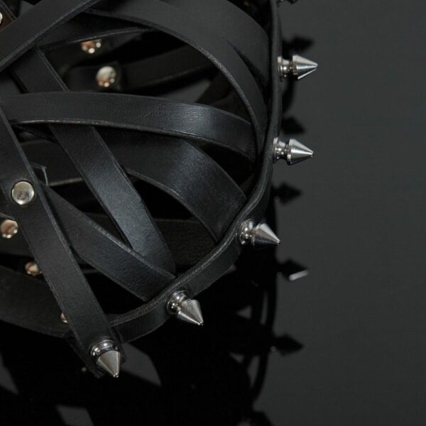 Packshot-Detail der Seite einer Maske aus Lederriemen in Schwarz mit silbernen Stacheln