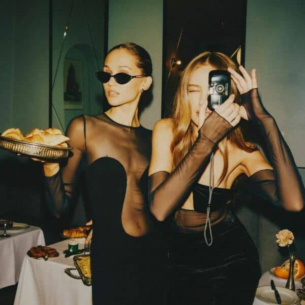 UNDRESS CODE - Robe Sleek Silhouette et Bisou Bodysuit couleur noir Photo de 2 Femmes de Devant portant une Robe avec Empiècements en Résille et Viscose à Manches Longues couleur Noir et un Body en résille avec Soutien-Gorge Croisé autour du Cou Opaque couleur Noir