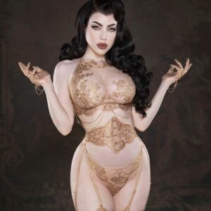 Le corset taille AIMÉE incarne l’élégance ultime, réalisé à la main avec de la dentelle Leavers française en or rosé et un tulle ultra-transparent pour un galbe parfait. Des crochets et œillets dorés, cousus avec soin, et un laçage au dos permettent une coupe personnalisée. Sa structure renforcée, dotée de baleines souples, met en valeur la taille, tandis que les bretelles doubles amovibles offrent une flexibilité maximale. Associez-le à la culotte brésilienne taille haute AIMÉE, également confectionnée avec la plus fine dentelle Leavers, ornée de cristaux dorés et de chaînes amovibles, pour un effet somptueux. Le soutien-gorge long AIMÉE, avec ses détails raffinés, apporte une touche précieuse, à porter seul ou comme pièce de style extérieur. Enfin, les mitaines en dentelle AIMÉE, ornées de cristaux et de chaînes dorées, apportent la touche finale parfaite à ce set de lingerie de luxe, rehaussant l’ensemble d’un éclat unique.