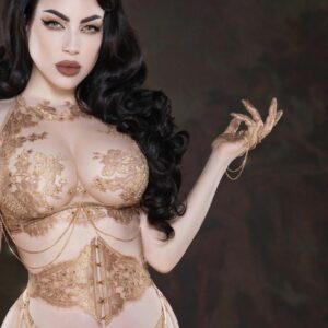 The AIMÉE corset and long bra are handcrafted with rose-gold French Leavers lace, ultra-transparent tulle and sparkling crystals. Their soft whalebone structure and back lacing ensure a personalized fit. Matching mittens, adorned with gold crystals and chains, add a precious touch. Each piece is crafted in Barcelona with luxury materials, including viscose, nylon and polyester, and 24-carat gold-plated hardware.