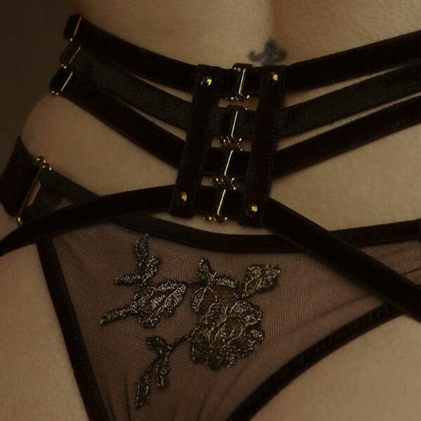Nahaufnahme einer Frau von hinten, die einen Netz-String und Strumpfhalter aus schwarzen, elastischen Samtbändern trägt