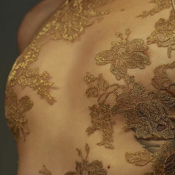 El body halter AMMALIE realza la silueta con su efecto segunda piel y su sutil brillo dorado. Confeccionado en punto ilusión ultratransparente, se ciñe al cuerpo con delicadeza. Su aplicación de encaje francés Leavers en oro rosa, cortada y cosida a mano, añade un toque precioso. Los tirantes dorados ajustables y los herrajes chapados en oro de 24 quilates garantizan un ajuste perfecto. Para un confort óptimo, el interior está forrado de algodón orgánico de bambú.