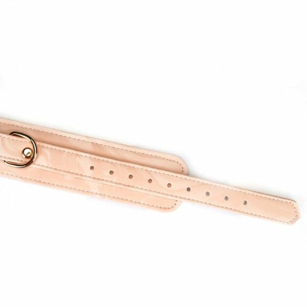 Boudoir Amor handcuffs in pastel pink and black vegan imitation leather. Gold-plated finish, D-ring for fastening. Adjustable buckles and quick-release clips for security and comfort. Ideal for elegant submission play.