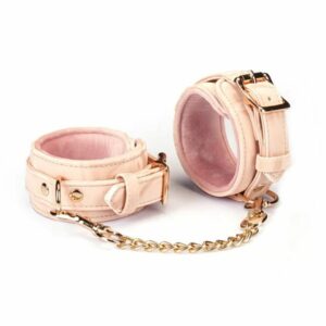 Handschellen Boudoir Amor aus veganem Kunstleder in Pastellrosa und Schwarz. Vergoldete Beschläge, D-Ring zur Befestigung. Verstellbare Schnallen und schnell lösbare Clips für Sicherheit und Komfort. Ideal für elegante Unterwerfungsspiele.