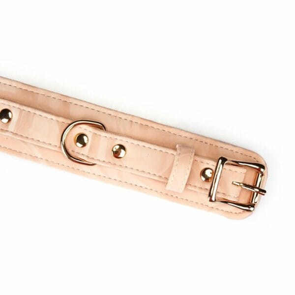 Boudoir Amor handcuffs in pastel pink and black vegan imitation leather. Gold-plated finish, D-ring for fastening. Adjustable buckles and quick-release clips for security and comfort. Ideal for elegant submission play.