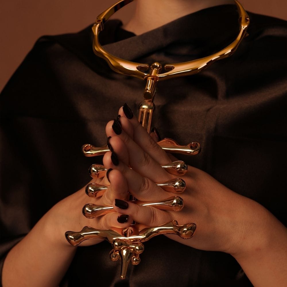 Mujer de frente con collar de oro y juego de pinzas para los dedos