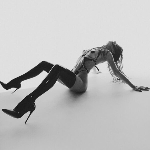 Femme Couchée Portant un Harnais En Cuir Rouge avec Chaînes et Anneau Dorés