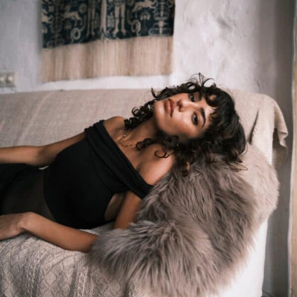 Undress Code – Body Libra | Brigade Mondaine Paris Body noir Undress Code Libra à épaules dégagées, porté par un modèle tenant une coupe de champagne, sélection Brigade Mondaine Paris.