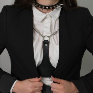 Frau trägt den Choker 86137 mit weißem Hemd, schwarzem Blazer und schwarzem Ledergeschirr, das mit silbernen Ketten verziert ist. Der Choker ist mit Metallspikes verziert und wird hinten mit einer verstellbaren Schnalle geschlossen.