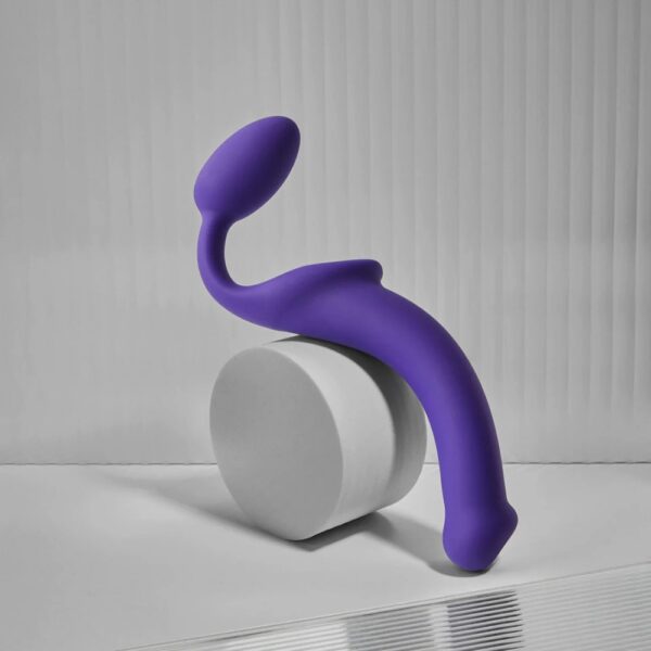 STRAP-ON-ME Strap-on original violet – Sélection Brigade Mondaine Paris Plug strapless violet STRAP-ON-ME au design courbé et ergonomique, posé sur un socle minimaliste, sélection Brigade Mondaine Paris.