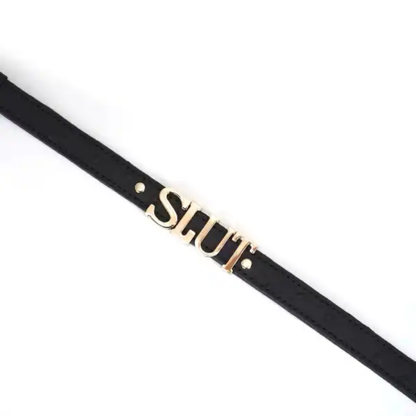 Gargantilla de cuero negro repujado con letras plateadas SLUT y ribetes dorados. Un accesorio ajustable, flexible y cómodo, perfecto para juegos BDSM y conjuntos fetichistas.