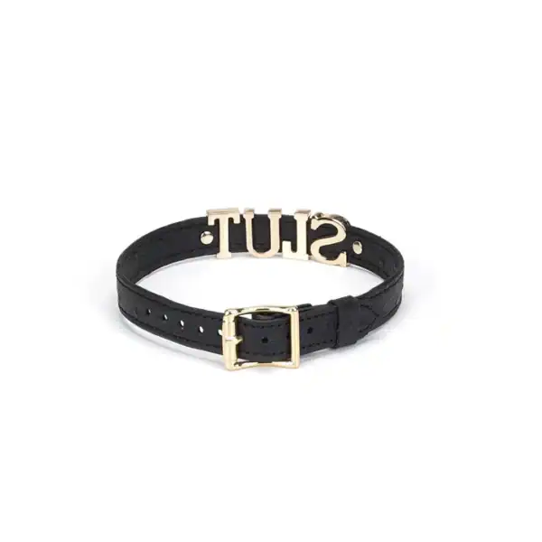 Gargantilla de cuero negro repujado con letras plateadas SLUT y ribetes dorados. Un accesorio ajustable, flexible y cómodo, perfecto para juegos BDSM y conjuntos fetichistas.
