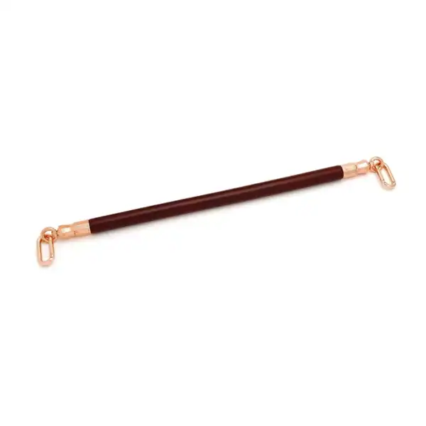 Spreizstange aus weinrotem Leder mit einem Kern aus Eukalyptusholz. O-Ringe aus roségoldfarbenem Metall zur Befestigung von Knöchelschienen. Elegant und funktional für raffinierte BDSM-Spiele.