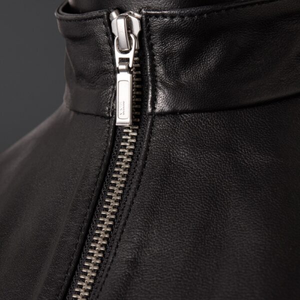 Top en cuir de mouton noir zippé à col montant zip central et dos entièrement ouvert à nouer La coupe est droite, couvrante. La matière, elle, ne cache rien.