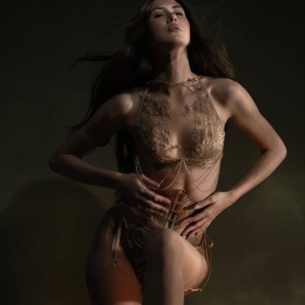 Aimée Korsett Strapsgürtel - CELINE-MARIE bei Brigade Mondaine Paris Aimée Strumpfhalterkorsett der Marke CELINE-MARIE, ausgewählt von Brigade Mondaine Paris, getragen von einem Model in dunklem Studio, das die Struktur des Korsetts, die eingearbeiteten Strumpfhalter und die raffinierten Details hervorhebt.