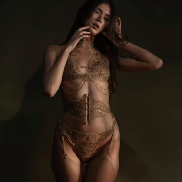 Aimée Korsett Strapsgürtel - CELINE-MARIE bei Brigade Mondaine Paris Aimée Strumpfhalterkorsett der Marke CELINE-MARIE, ausgewählt von Brigade Mondaine Paris, getragen von einem Model in dunklem Studio, das die Struktur des Korsetts, die eingearbeiteten Strumpfhalter und die raffinierten Details hervorhebt.