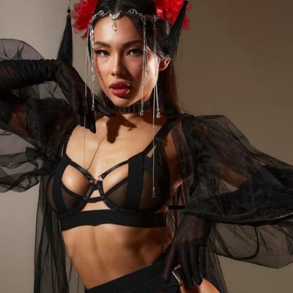 Geisha-Dessous aus schwarzem Tüll mit frischen Ausschnitten und elastischen Bändern. Offenes Höschen, Strapsgürtel, BH und Choker passend dazu. Metallische Details und präzise Passform. Grafische Linie von Pivovarova. Handgefertigt in der Ukraine.
