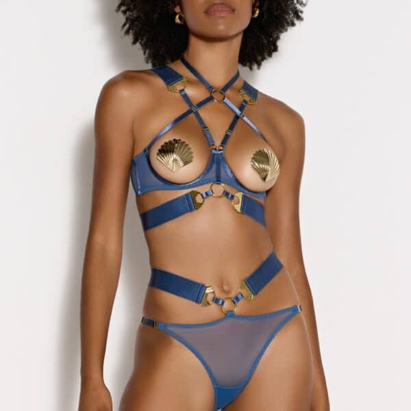Vue face de l’ensemble ouvert BORDELLE bleu avec soutien-gorge à harnais, coques métalliques dorées en forme de coquille, bretelles croisées et tanga ouvert en tulle.