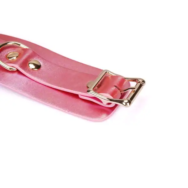 Handschellen Lustre Rosa LIEBE SEELE aus rosafarbenem Glattleder mit goldenen Metallnieten und verstellbarem Riemen, präsentiert auf weißem Hintergrund