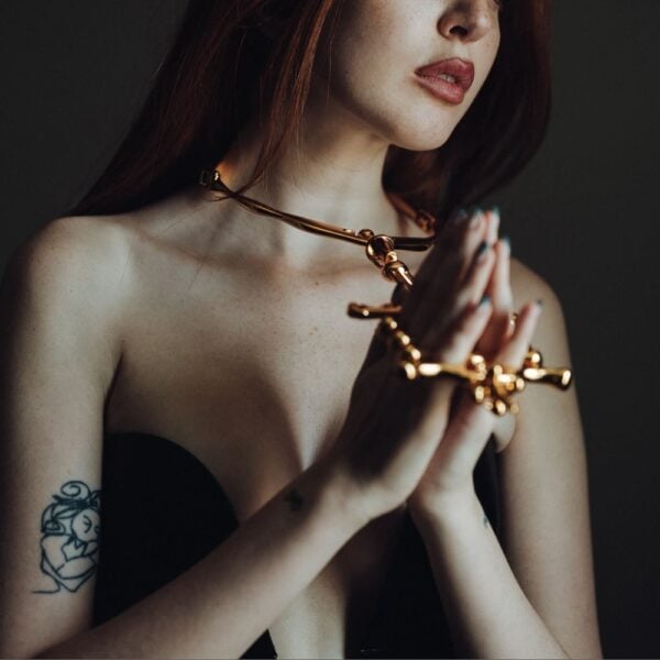 Collier et menottes BDSM en métal doré UPKO – Brigade Mondaine Paris Collier et menottes BDSM UPKO en métal doré portés ensemble dans une mise en scène éditoriale Brigade Mondaine Paris